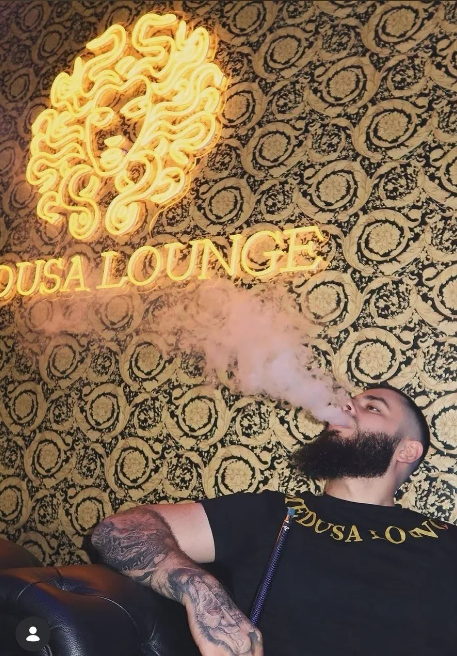 Guest smoking hookah under Medusa Lounge neon sign